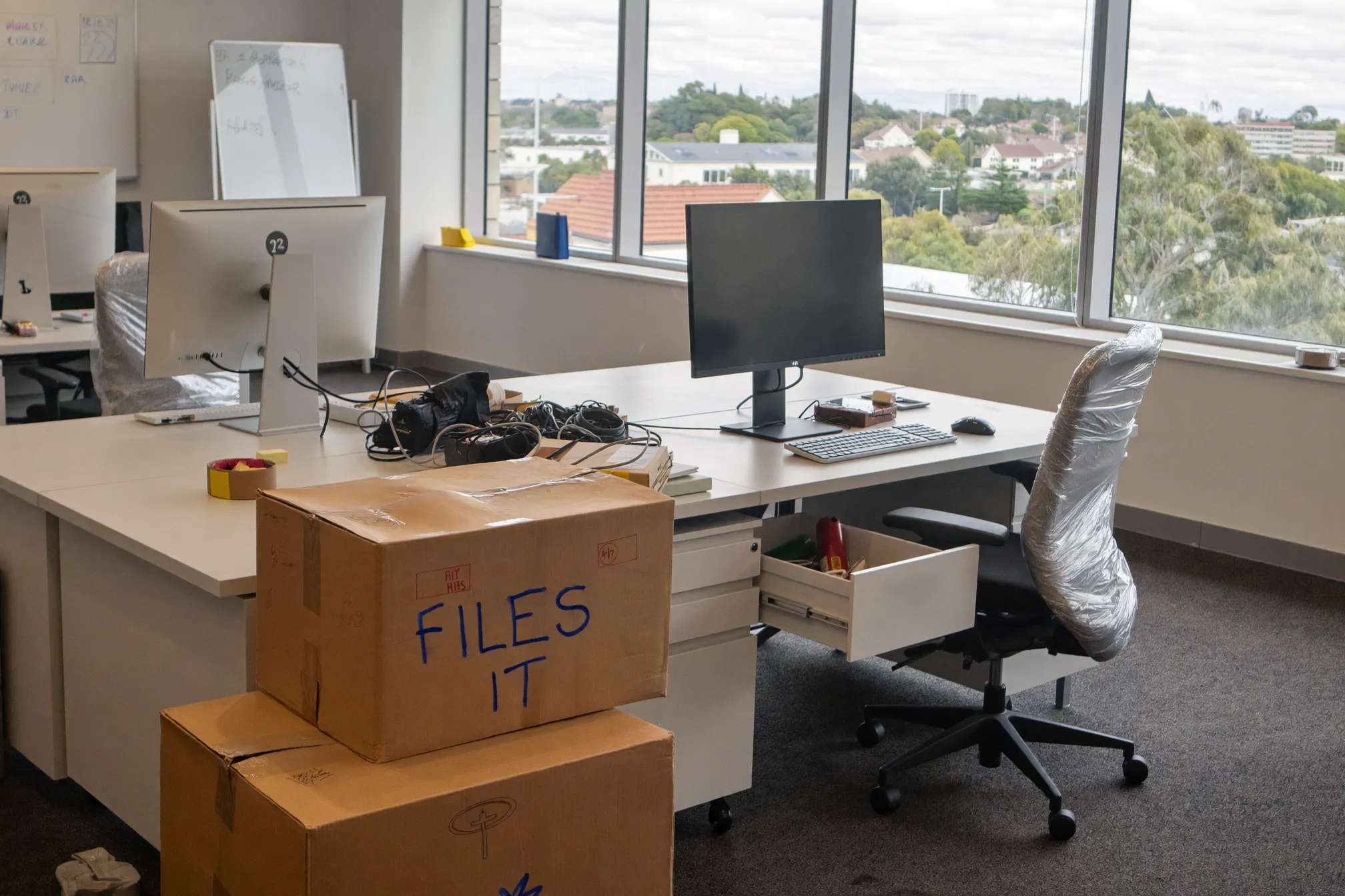 Office packed for relocation with wrapped chairs and labelled boxes