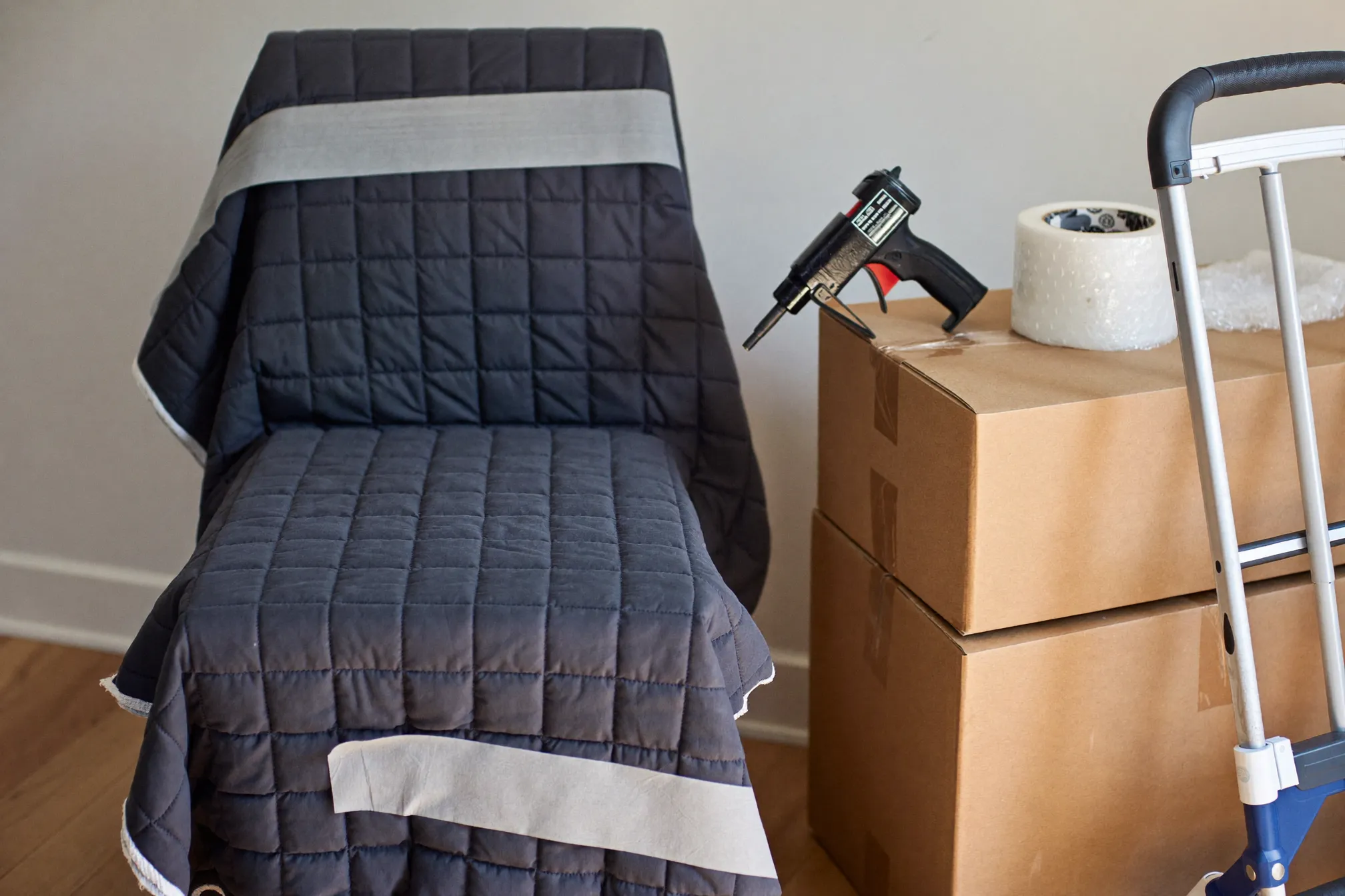 Furniture wrapped in protective moving blankets beside packed boxes